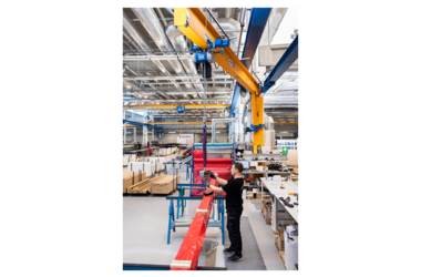 Employee uses column-mounted slewing crane in production hall of Stalprofil company