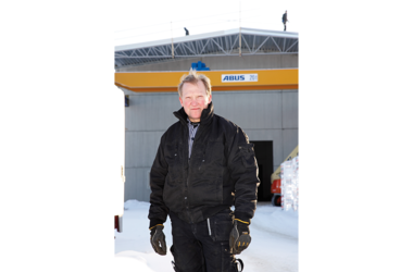 Employee standing in front of industrial hall where ABUS double girder overhead travelling crane ZLK can be seen in the background 