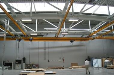 Crane operator controls overhead travelling crane with trolley in production hall in Austria