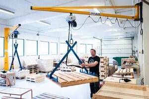 Employee operates wall jib crane in workshop for the disabled in Norway