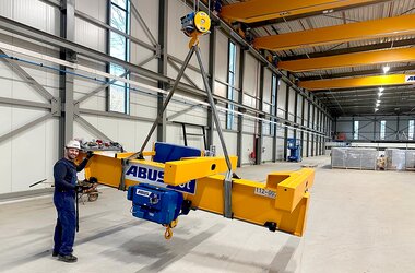 The main girder of a Semi-Goliath crane is lifted into place for assembly using a wire rope hoist.