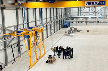 There are two semi-goliath cranes in a factory building, with an overhead travelling crane on an upper level.