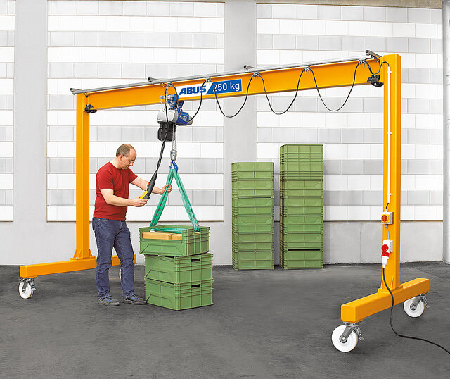 An employee operates a suspended rail system with a chain hoist and moves a load in a factory