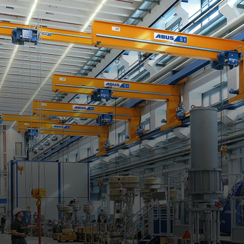 ABUS wall travelling cranes in an industrial hall with a load capacity of up to 5 tons and a span of up to 12 meters for the efficient servicing of multiple workstations.